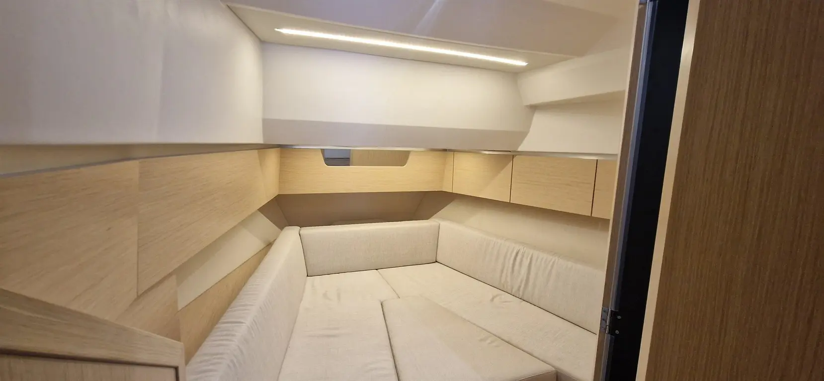 A modern, minimalistic cabin featuring a beige sofa, wooden panels, and soft lighting fixtures, creating a calming atmosphere.